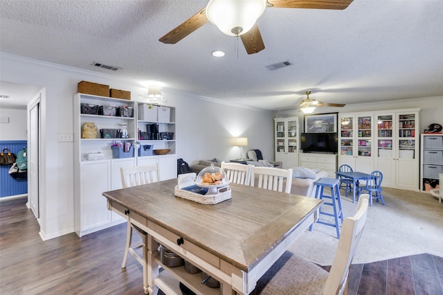 dining room with dark wood-type flooring, a textured ceiling, and ornamental molding