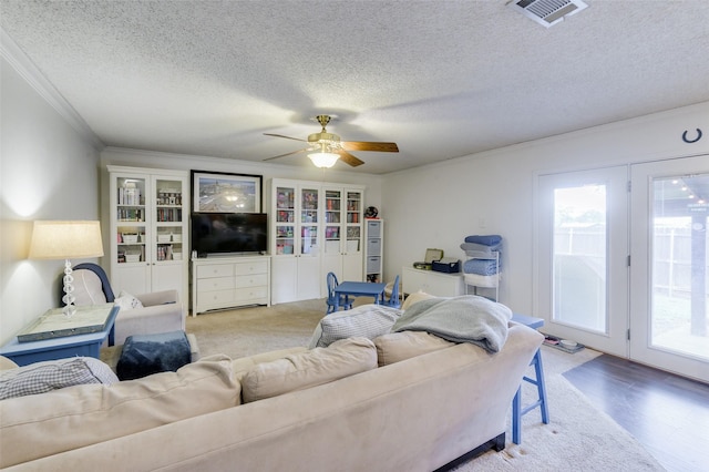 living room with ceiling fan, crown molding, and a textured ceiling