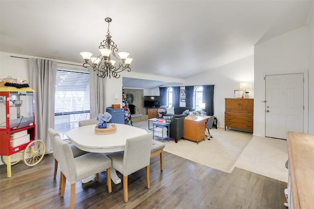 dining room featuring lofted ceiling, plenty of natural light, wood-type flooring, and an inviting chandelier