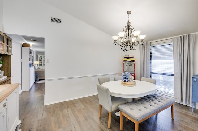 dining area featuring a chandelier, wood-type flooring, and vaulted ceiling