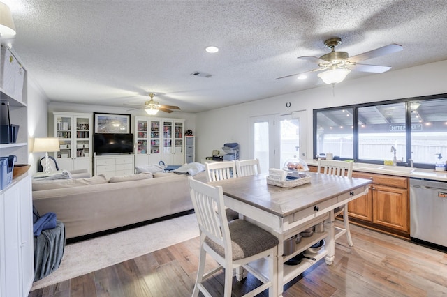 dining space with light wood-type flooring, a textured ceiling, ceiling fan, and sink