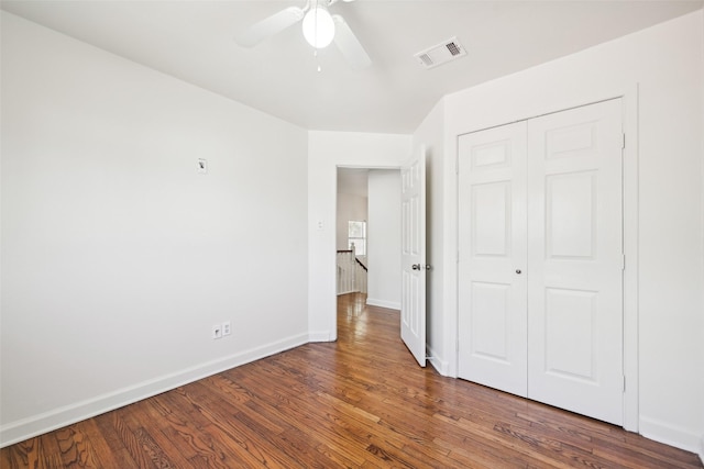 unfurnished bedroom with ceiling fan, dark hardwood / wood-style flooring, and a closet