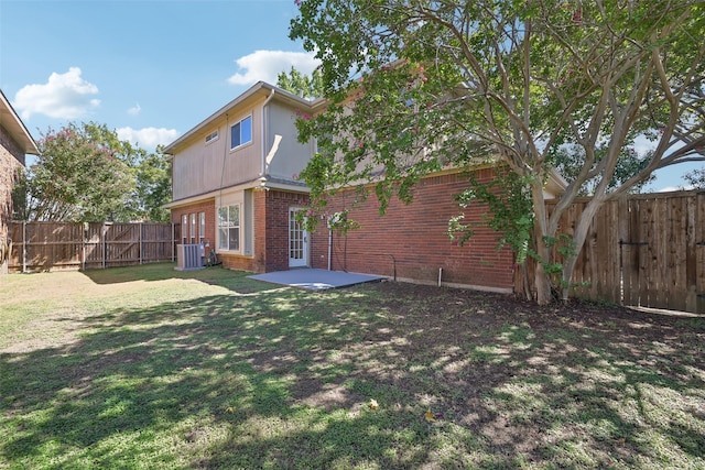 rear view of property with a yard, a patio, and central AC unit