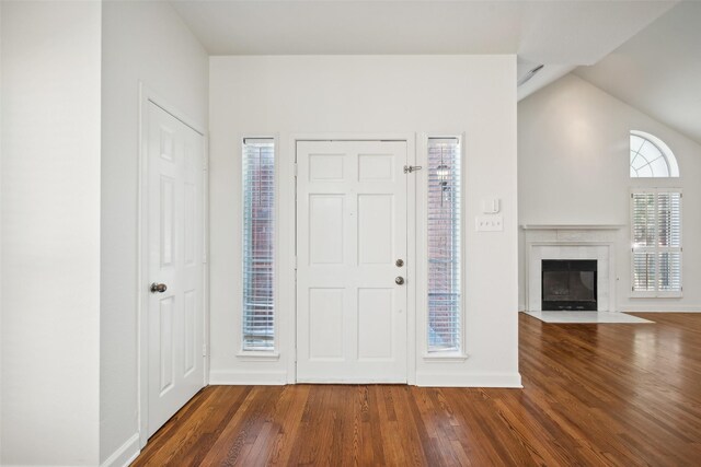 foyer entrance with a high end fireplace, vaulted ceiling, and hardwood / wood-style flooring