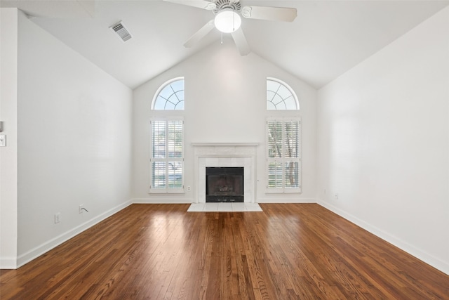 unfurnished living room with hardwood / wood-style flooring, ceiling fan, high vaulted ceiling, and a tile fireplace