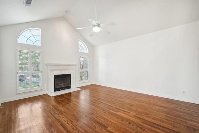 unfurnished living room featuring a tiled fireplace, plenty of natural light, high vaulted ceiling, and wood-type flooring