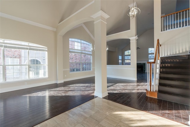 entryway with hardwood / wood-style flooring, a notable chandelier, crown molding, and high vaulted ceiling