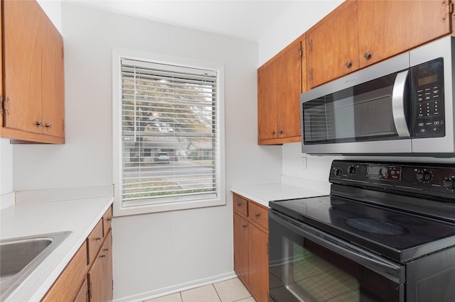 kitchen featuring a wealth of natural light, sink, light tile patterned floors, and black range with electric cooktop