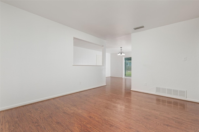 empty room featuring hardwood / wood-style floors and a notable chandelier