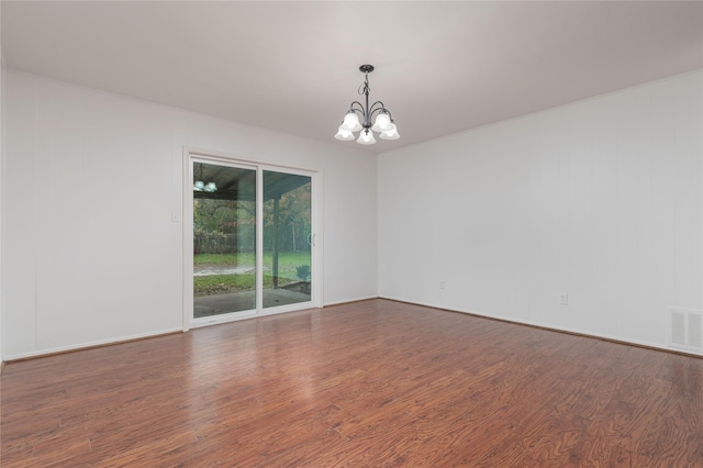 unfurnished room with a notable chandelier and dark hardwood / wood-style floors