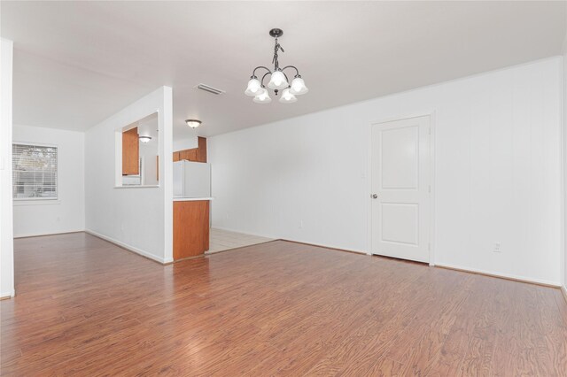 unfurnished room featuring a chandelier and hardwood / wood-style floors