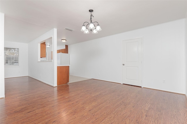 spare room featuring a notable chandelier and wood-type flooring