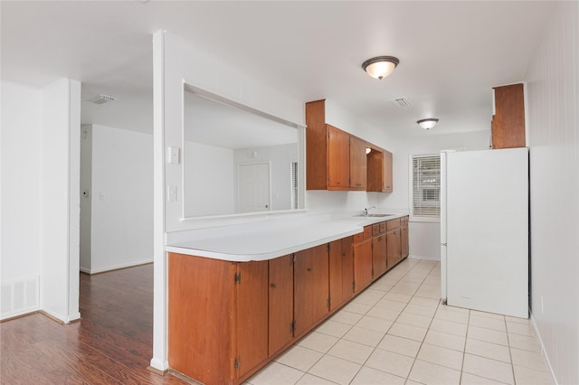 kitchen with light tile patterned flooring, white refrigerator, and sink