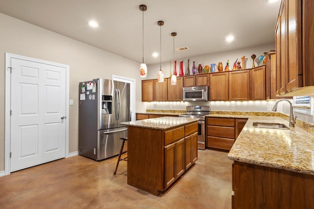 kitchen with light stone counters, stainless steel appliances, sink, decorative light fixtures, and a kitchen island