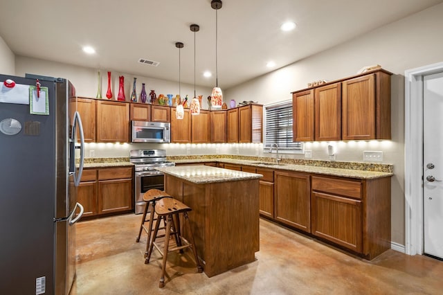 kitchen with a breakfast bar, a center island, sink, appliances with stainless steel finishes, and decorative light fixtures