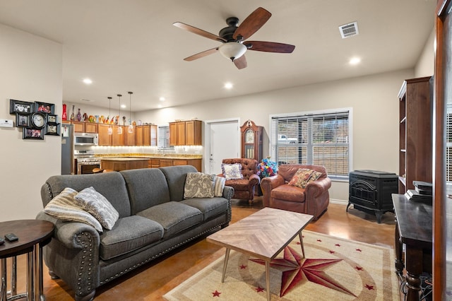 living room featuring ceiling fan and a wood stove