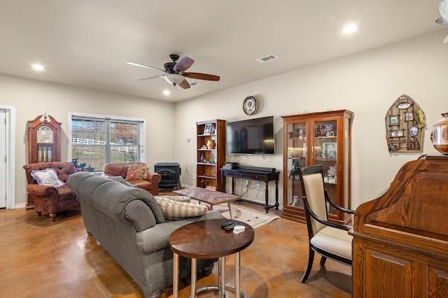 living room featuring a wood stove and ceiling fan