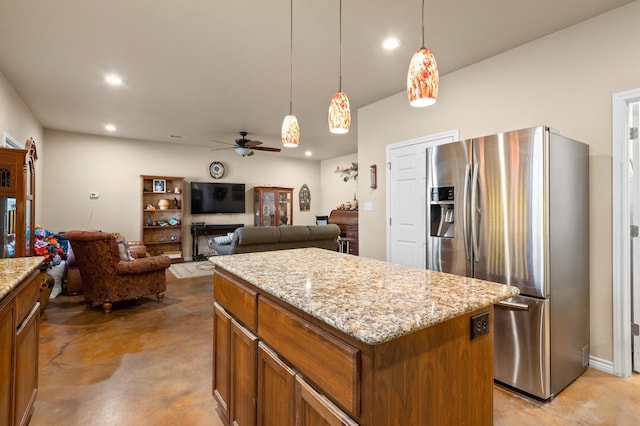 kitchen featuring stainless steel fridge, light stone counters, ceiling fan, decorative light fixtures, and a kitchen island