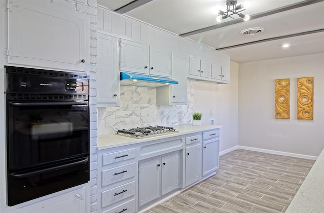 kitchen featuring double oven, white cabinets, backsplash, and stainless steel gas stovetop