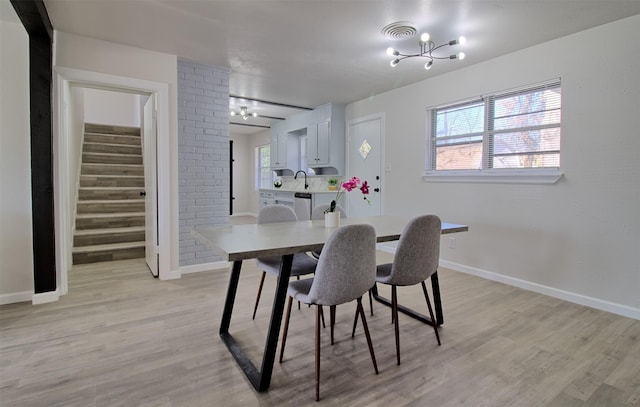 dining area with sink, plenty of natural light, a chandelier, and light wood-type flooring