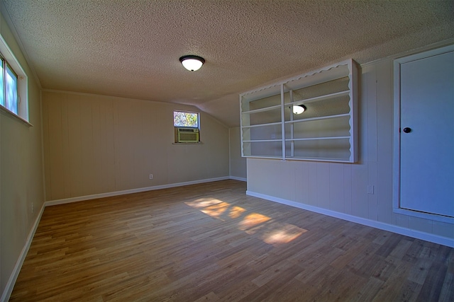 unfurnished room featuring hardwood / wood-style flooring, a textured ceiling, and cooling unit