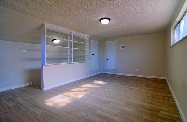 unfurnished room featuring hardwood / wood-style flooring and a textured ceiling