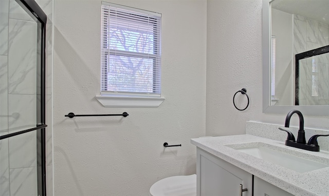 bathroom featuring vanity, an enclosed shower, and toilet