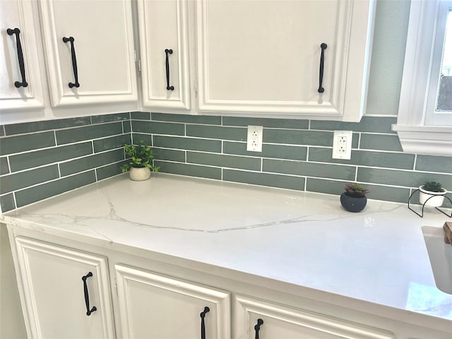 details featuring white cabinetry, light stone countertops, and tasteful backsplash