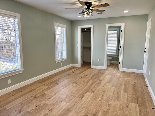 unfurnished bedroom featuring ensuite bath, ceiling fan, a spacious closet, light hardwood / wood-style floors, and a closet