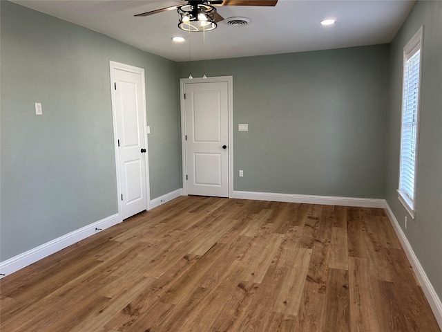 empty room featuring ceiling fan, wood-type flooring, and a wealth of natural light