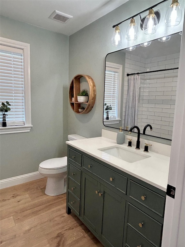 bathroom with wood-type flooring, vanity, toilet, and curtained shower