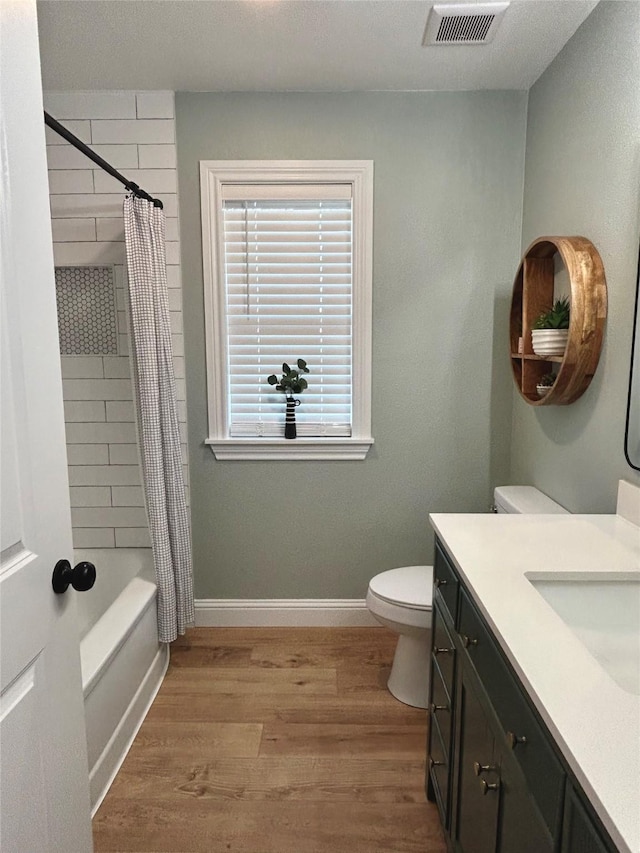 full bathroom featuring hardwood / wood-style floors, vanity, shower / bath combination with curtain, and toilet