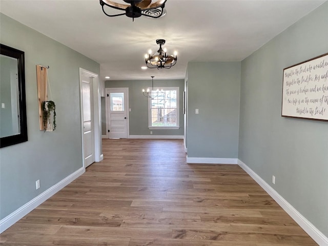 interior space with ceiling fan with notable chandelier and light hardwood / wood-style flooring