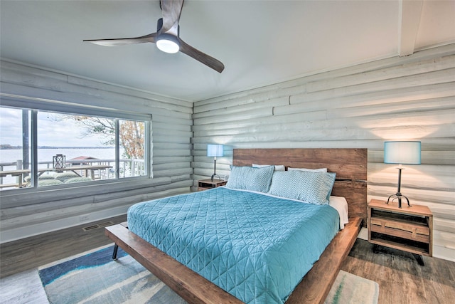 bedroom with hardwood / wood-style flooring, a water view, rustic walls, and ceiling fan