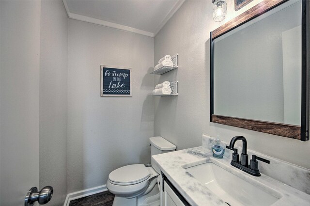 bathroom with vanity, toilet, wood-type flooring, and crown molding