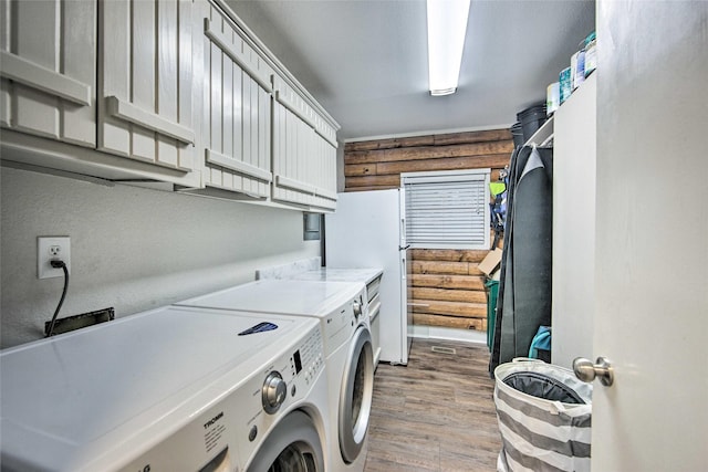 clothes washing area with cabinets, light hardwood / wood-style floors, and washing machine and dryer