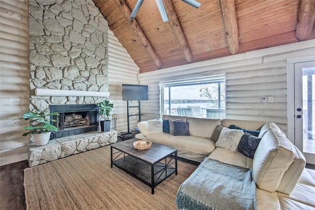 living room with a stone fireplace, beamed ceiling, log walls, and hardwood / wood-style flooring