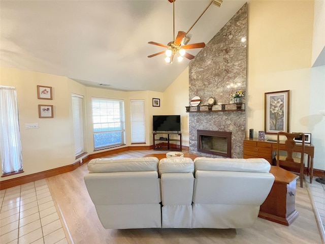 living room with ceiling fan, a large fireplace, high vaulted ceiling, and light hardwood / wood-style floors