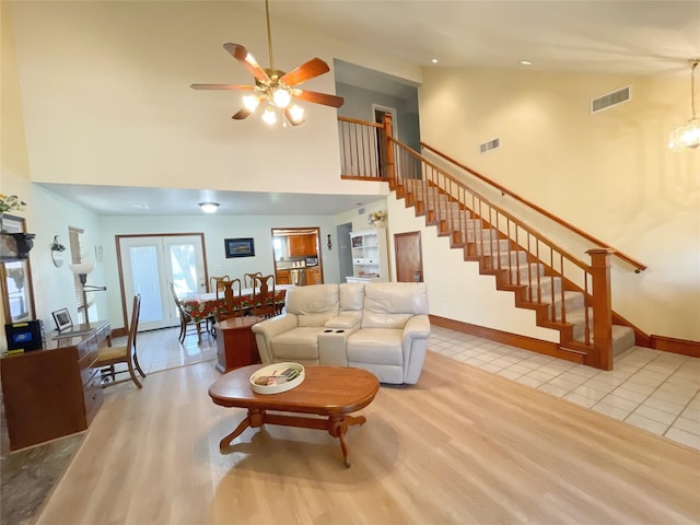 living room with light hardwood / wood-style flooring, a high ceiling, and ceiling fan