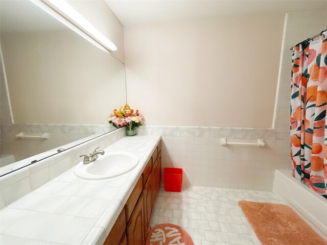 bathroom with shower / bath combo with shower curtain, tile walls, tile patterned floors, and vanity