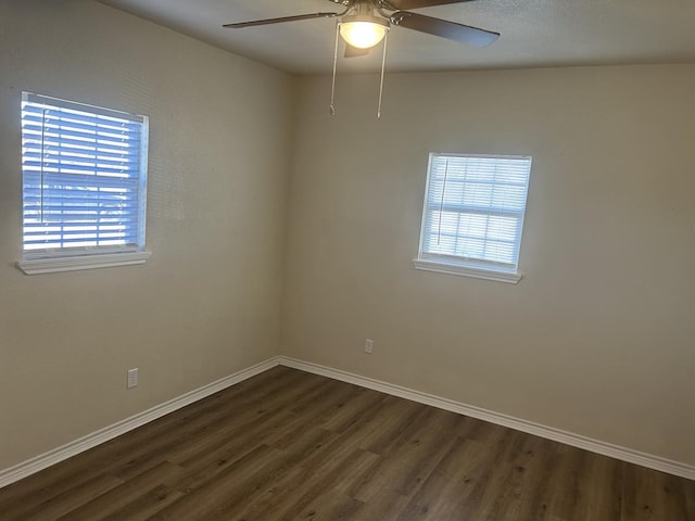 spare room with dark hardwood / wood-style flooring, ceiling fan, and a healthy amount of sunlight