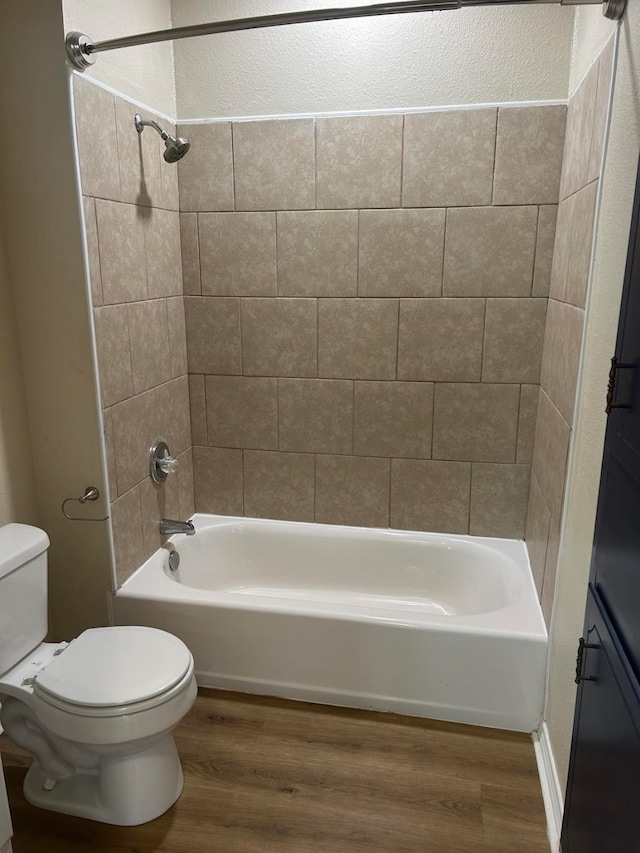 bathroom featuring hardwood / wood-style floors, toilet, and tiled shower / bath