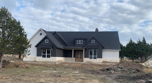 modern farmhouse style home featuring stone siding, french doors, and a chimney