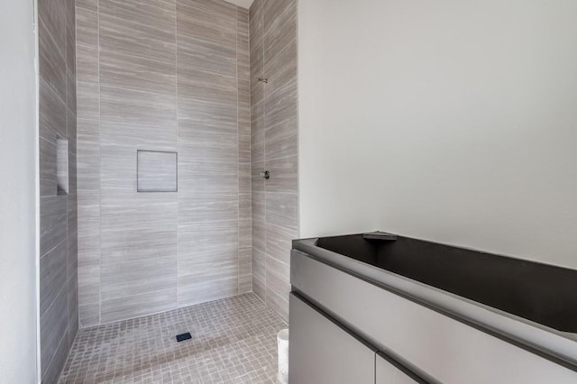 bathroom featuring tiled shower and vanity