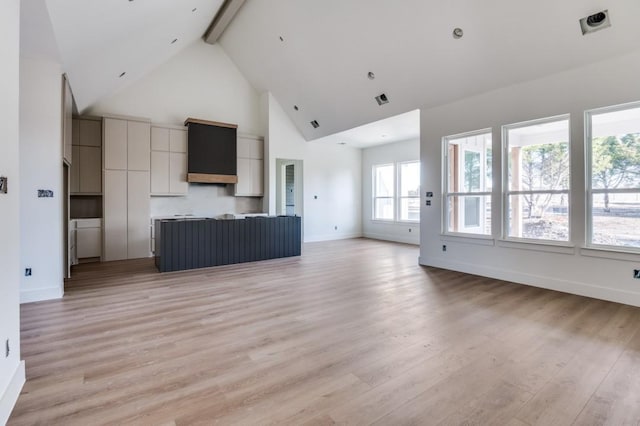 unfurnished living room with high vaulted ceiling, beam ceiling, and light hardwood / wood-style floors