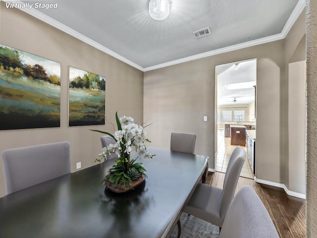 dining space featuring dark hardwood / wood-style floors, ornamental molding, and a textured ceiling