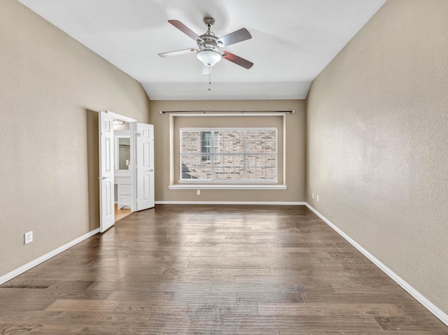 empty room featuring vaulted ceiling, ceiling fan, and dark wood-type flooring