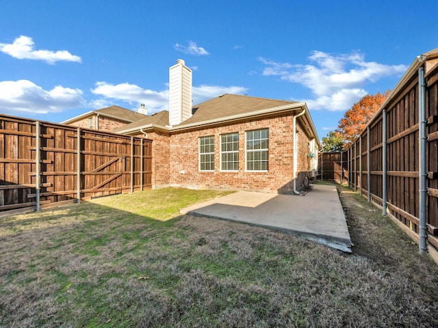 back of property with a yard and a patio area