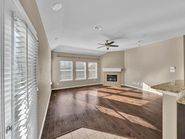 unfurnished living room with a tile fireplace, ceiling fan, light hardwood / wood-style floors, and lofted ceiling