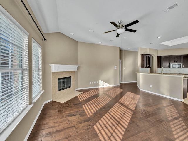 unfurnished living room with a tile fireplace, ceiling fan, sink, dark hardwood / wood-style flooring, and lofted ceiling